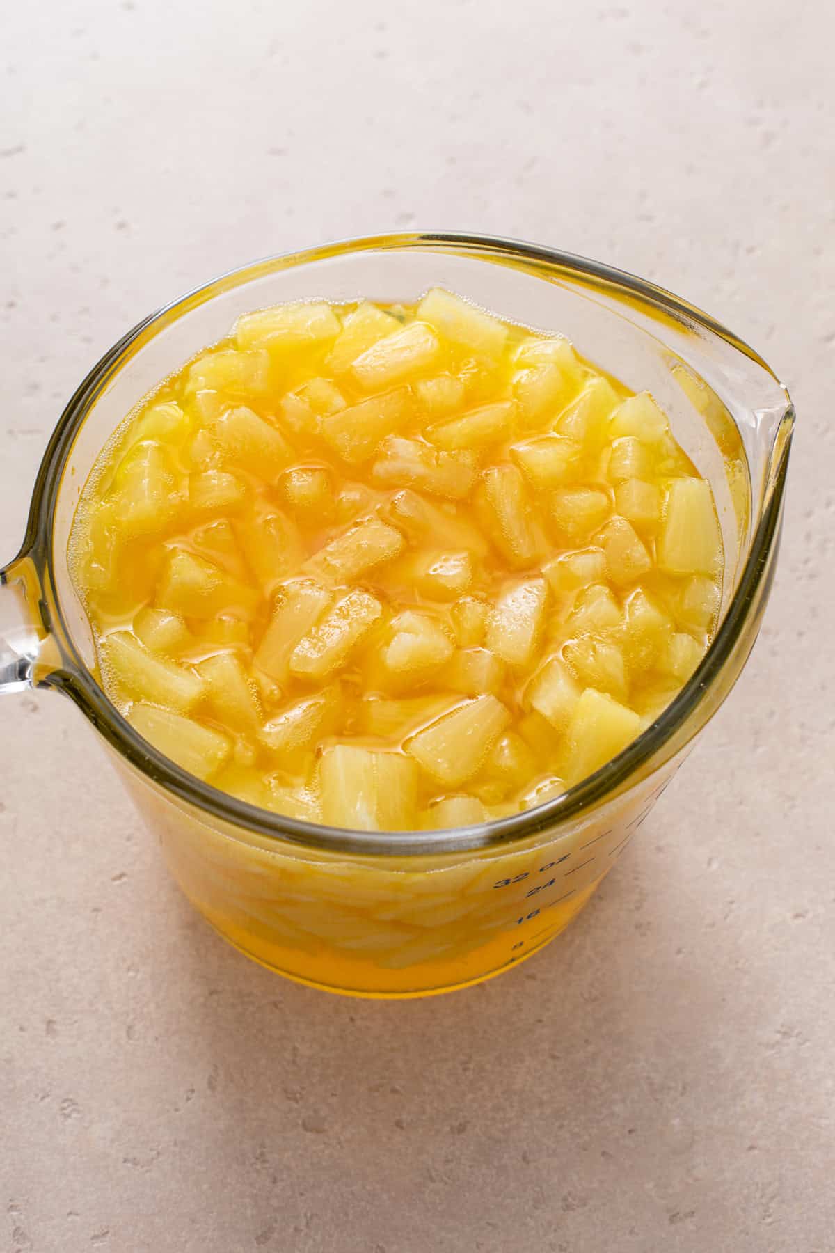 Pineapple jello mixture mixed in a large measuring cup.