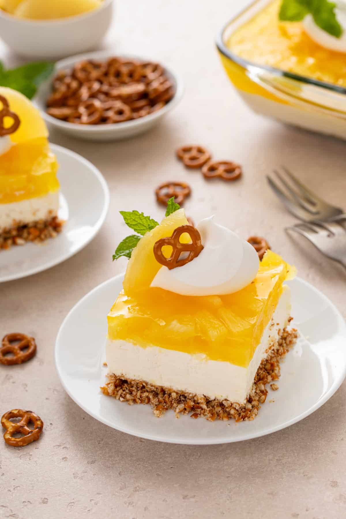 White plate holding a slice of pineapple pretzel salad.
