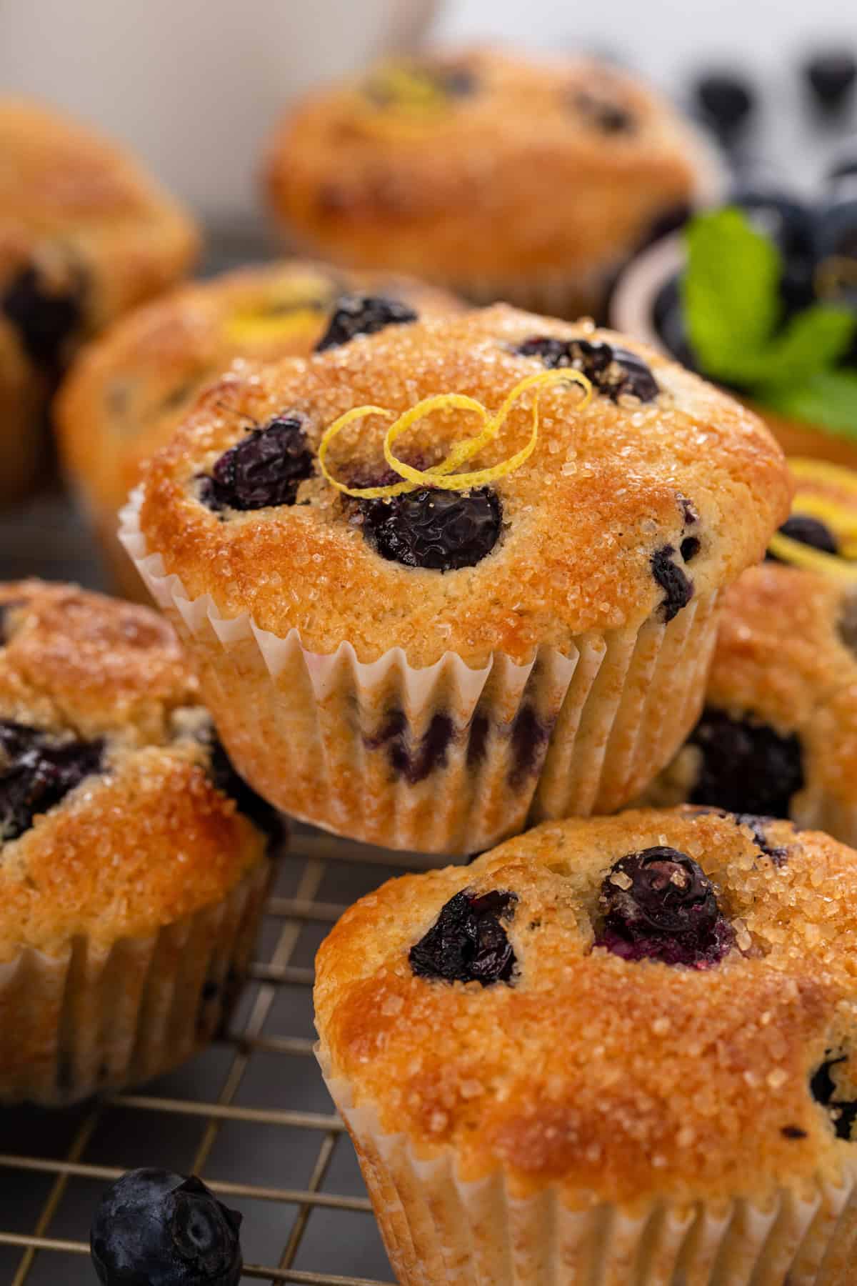 Lemon blueberry muffins stacked on top of each other on a wire rack.