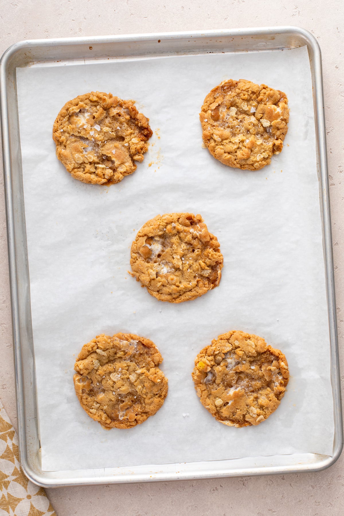 5 baked rice krispie cookies on a parchment-lined baking sheet.