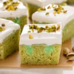 Slices of pistachio poke cake on a wooden board.