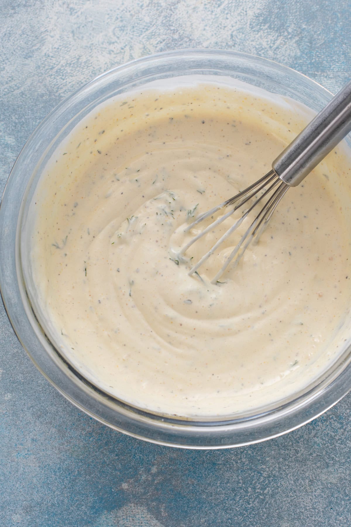 Dressing for dill pickle pasta salad whisked in a bowl.