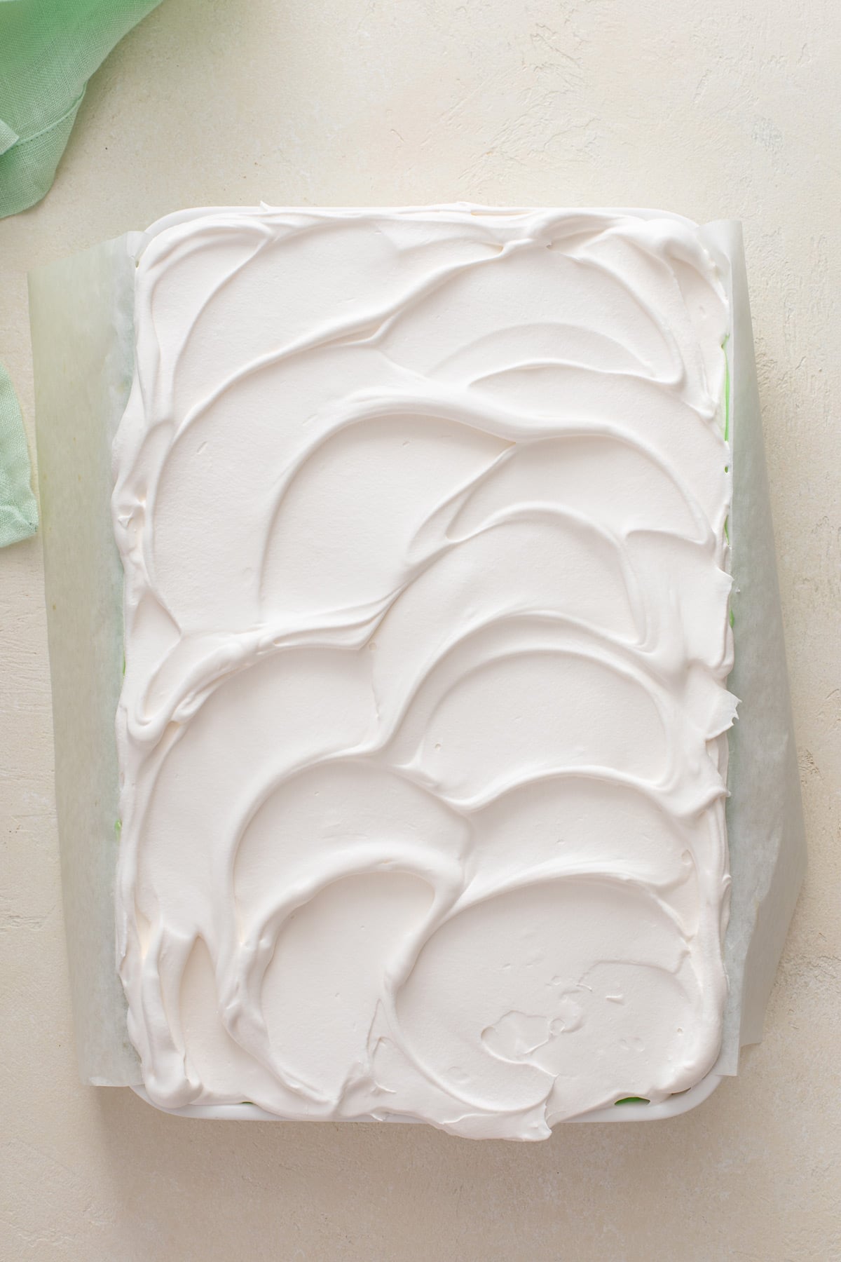Whipped topping spread over pistachio poke cake.