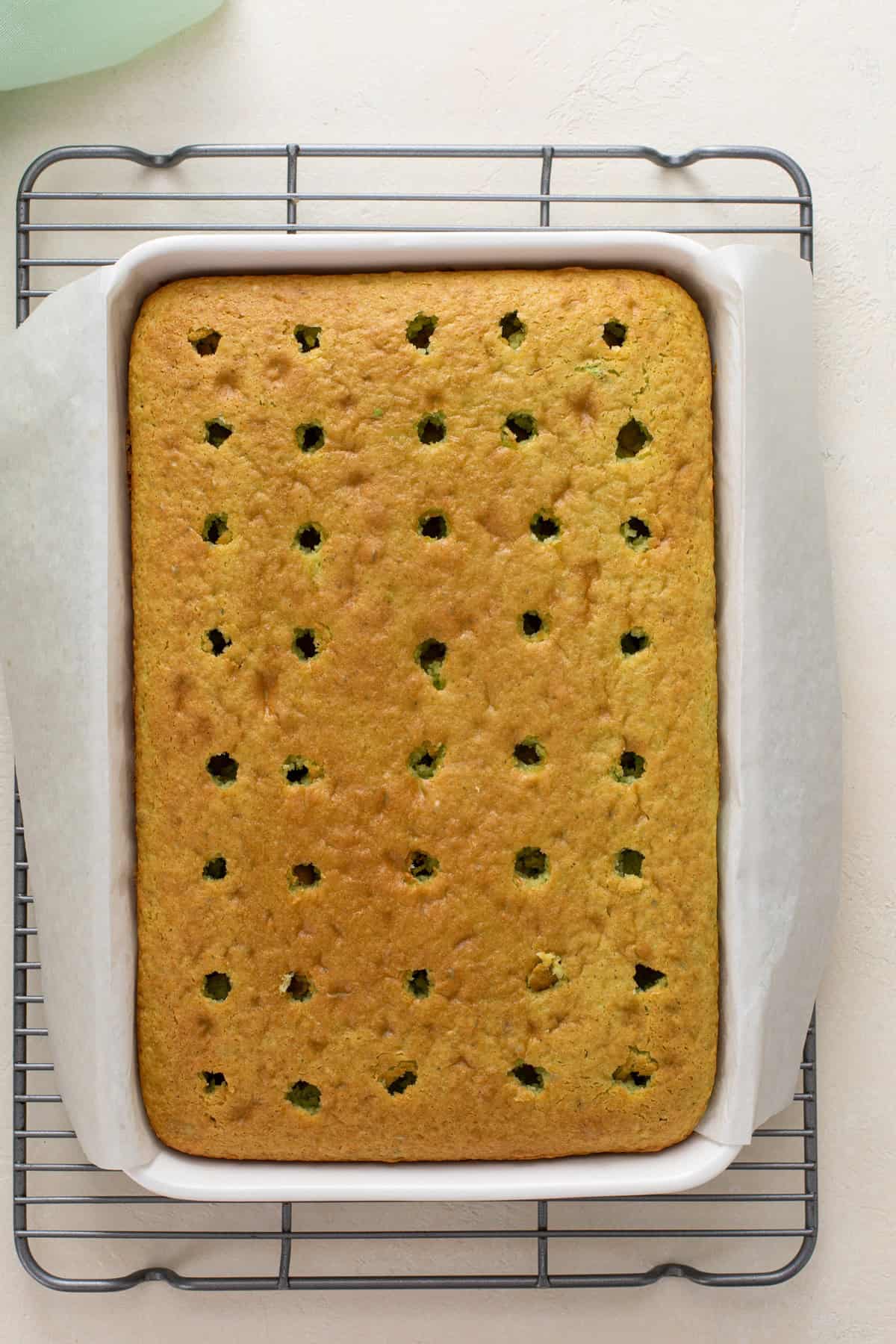 Baked pistachio cake with holes poked in the top.