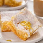 Close up of 2 slices of lemon gooey butter cake on a white plate.
