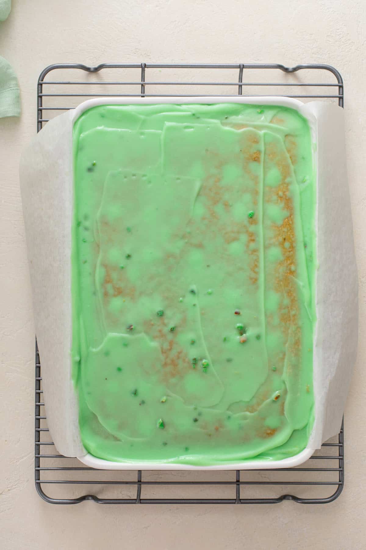 Pistachio pudding spread over a pistachio cake with holes in it.
