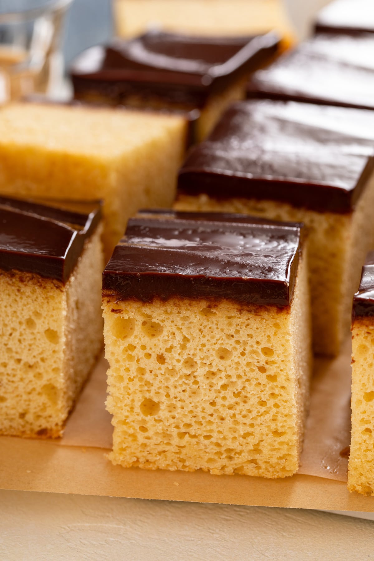 Close up of the side of a slice of yellow sheet cake with chocolate frosting to show the tender crumb.