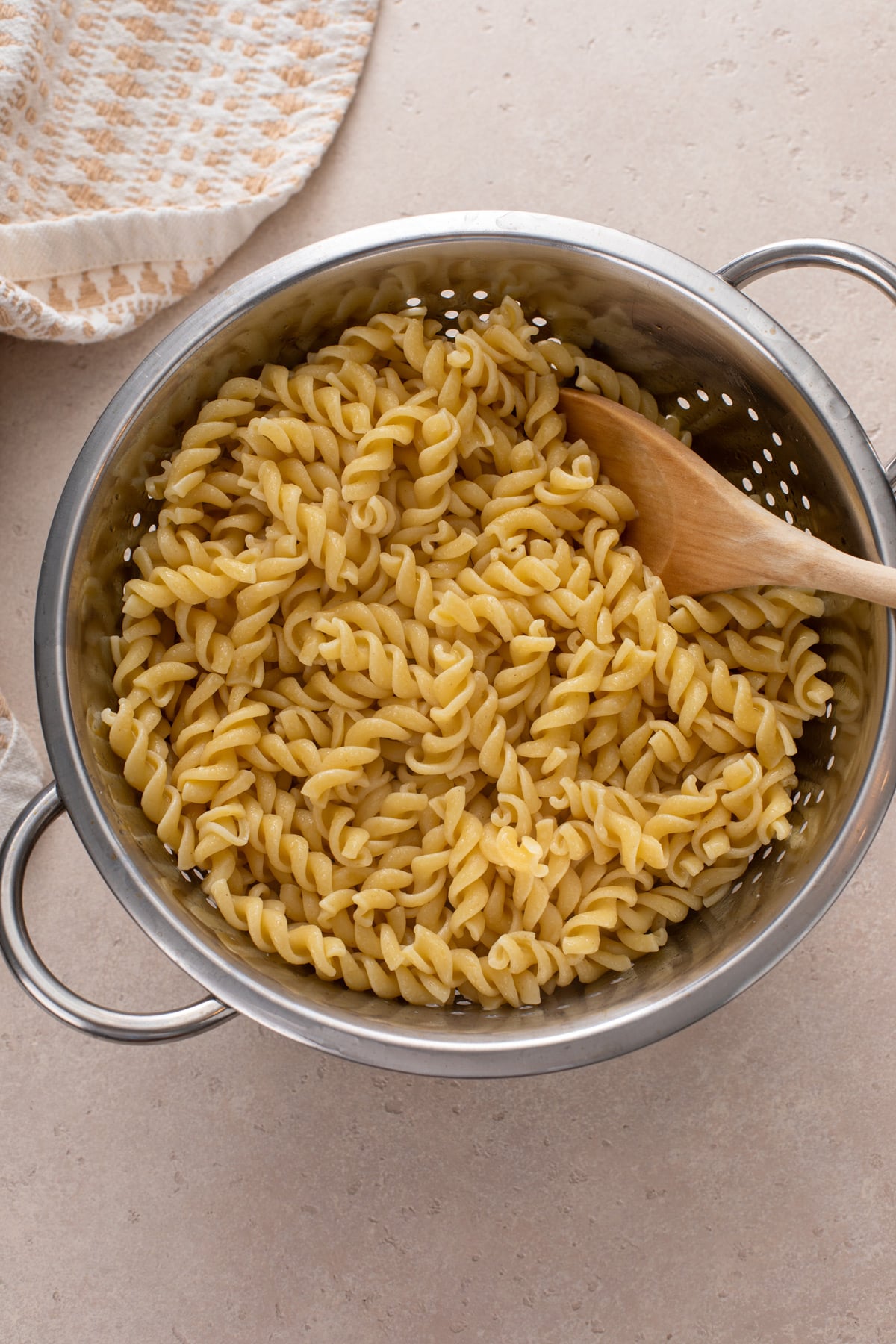 Cooked rotini pasta drained in a metal colander.