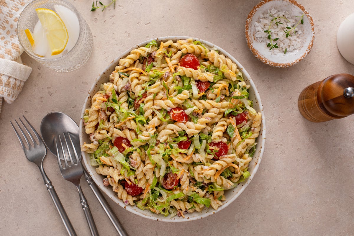 Overhead view of BLT pasta salad in a large white serving bowl on a countertop.