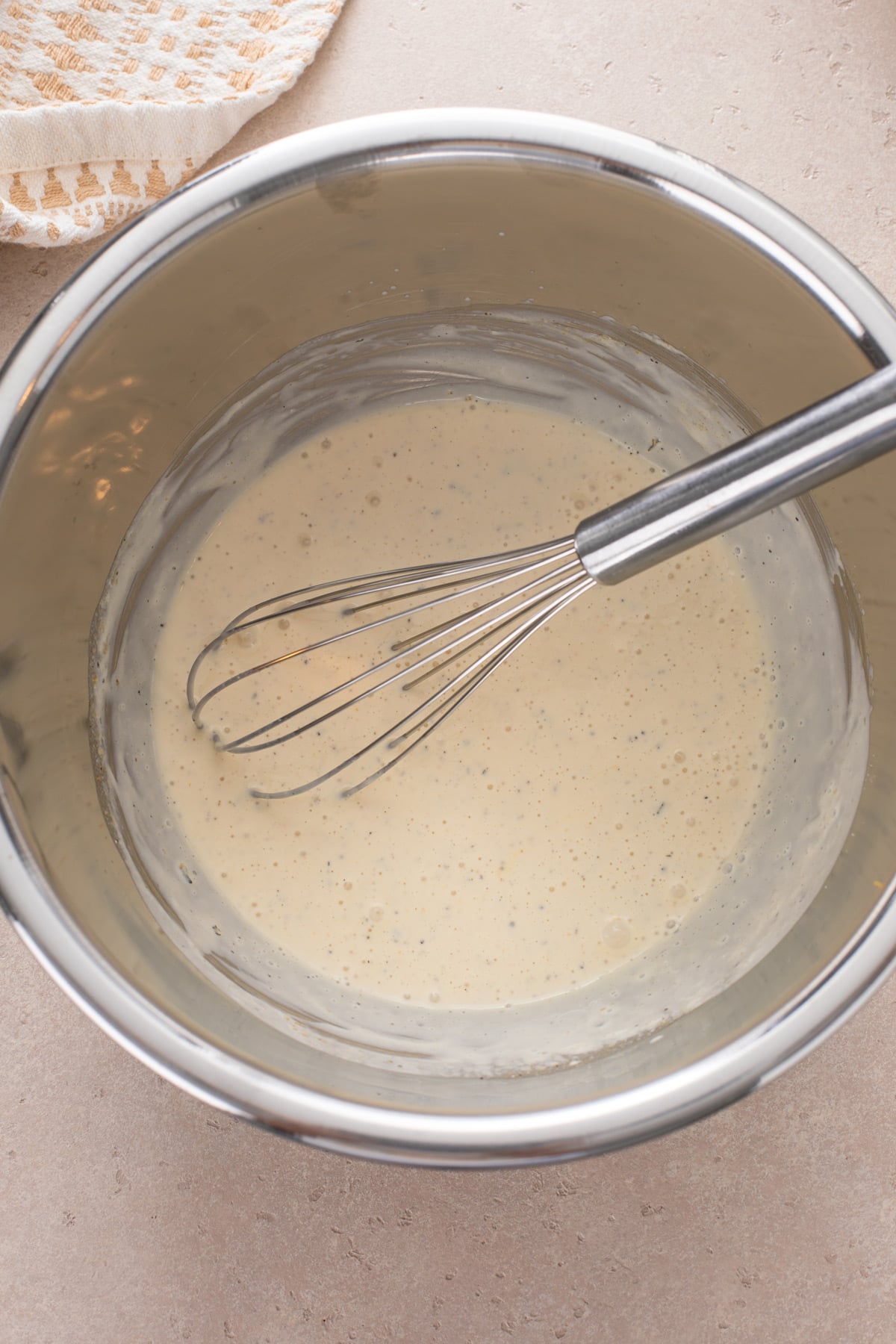 Dressing for BLT pasta salad whisked in a large metal mixing bowl.