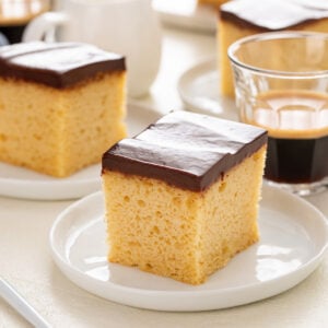 Plated slice of yellow sheet cake with chocolate frosting.