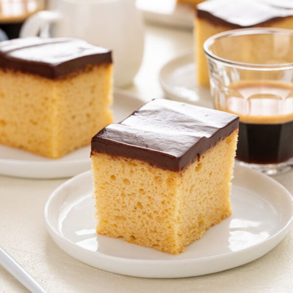 Plated slice of yellow sheet cake with chocolate frosting.