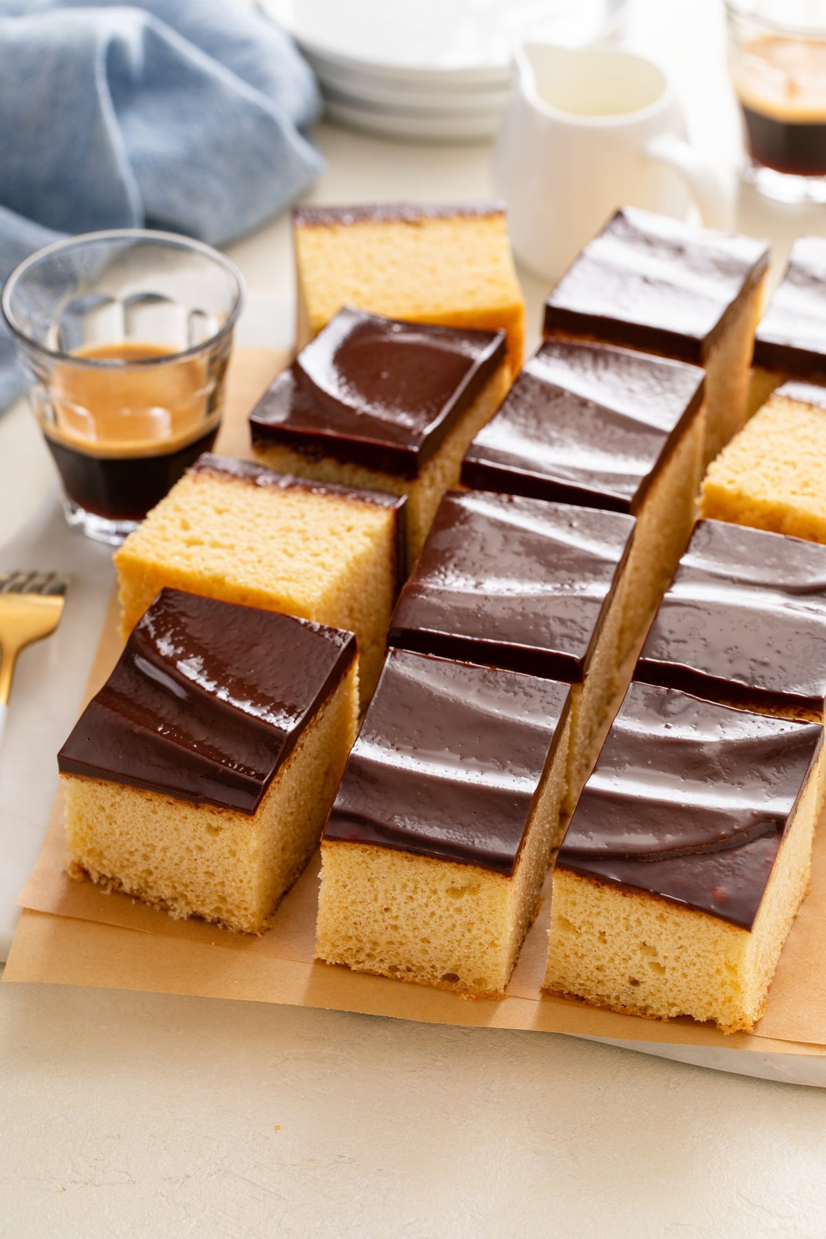 Slices of yellow sheet cake with chocolate frosting on a countertop.