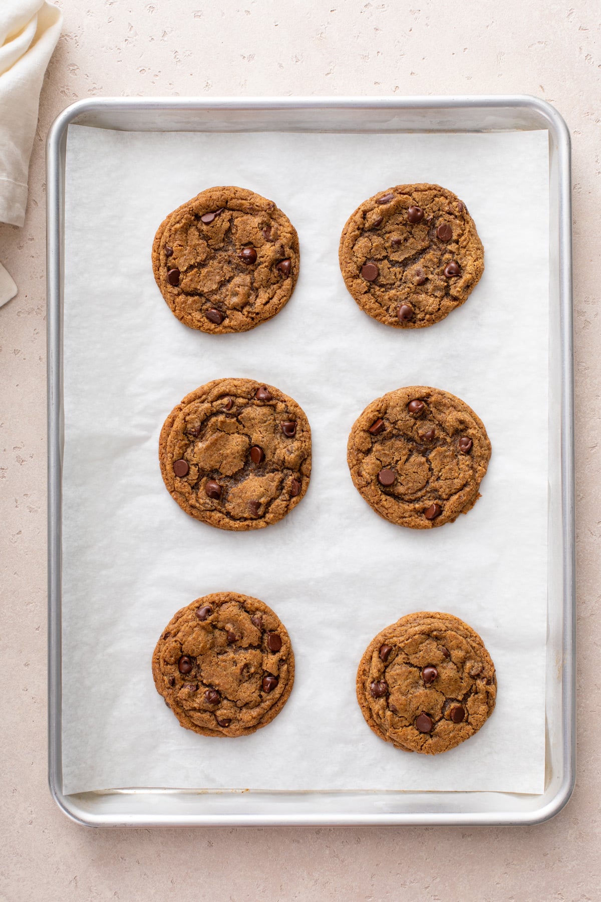 6 baked espresso chocolate chip cookies on a parchment-lined baking sheet.