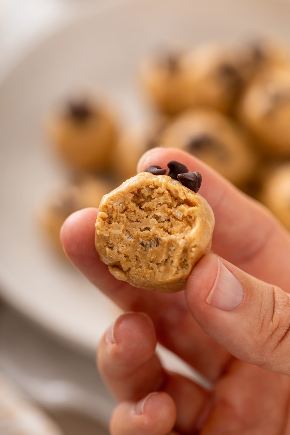 Hand holding up a peanut butter protein ball with a bite taken from it.
