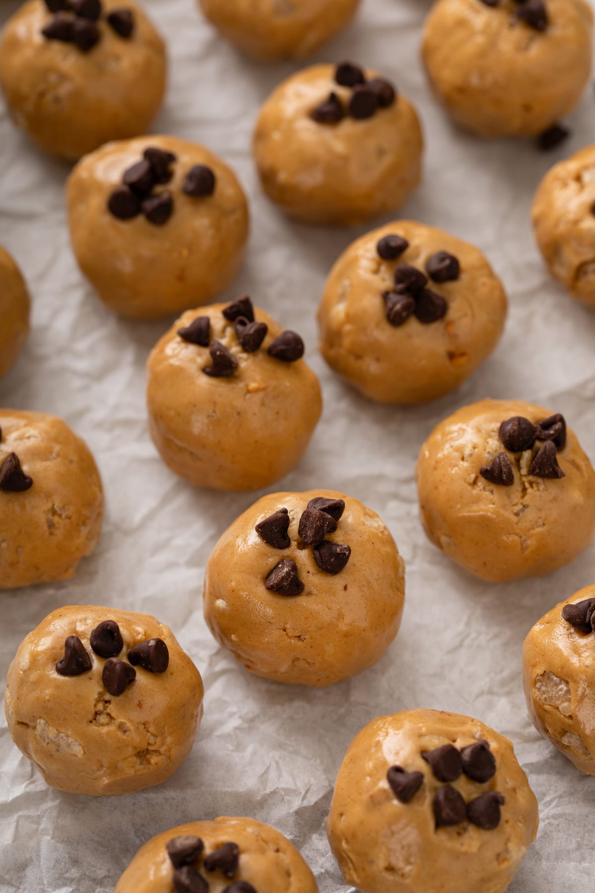 Rows of peanut butter protein balls arranged on a sheet of parchment paper.