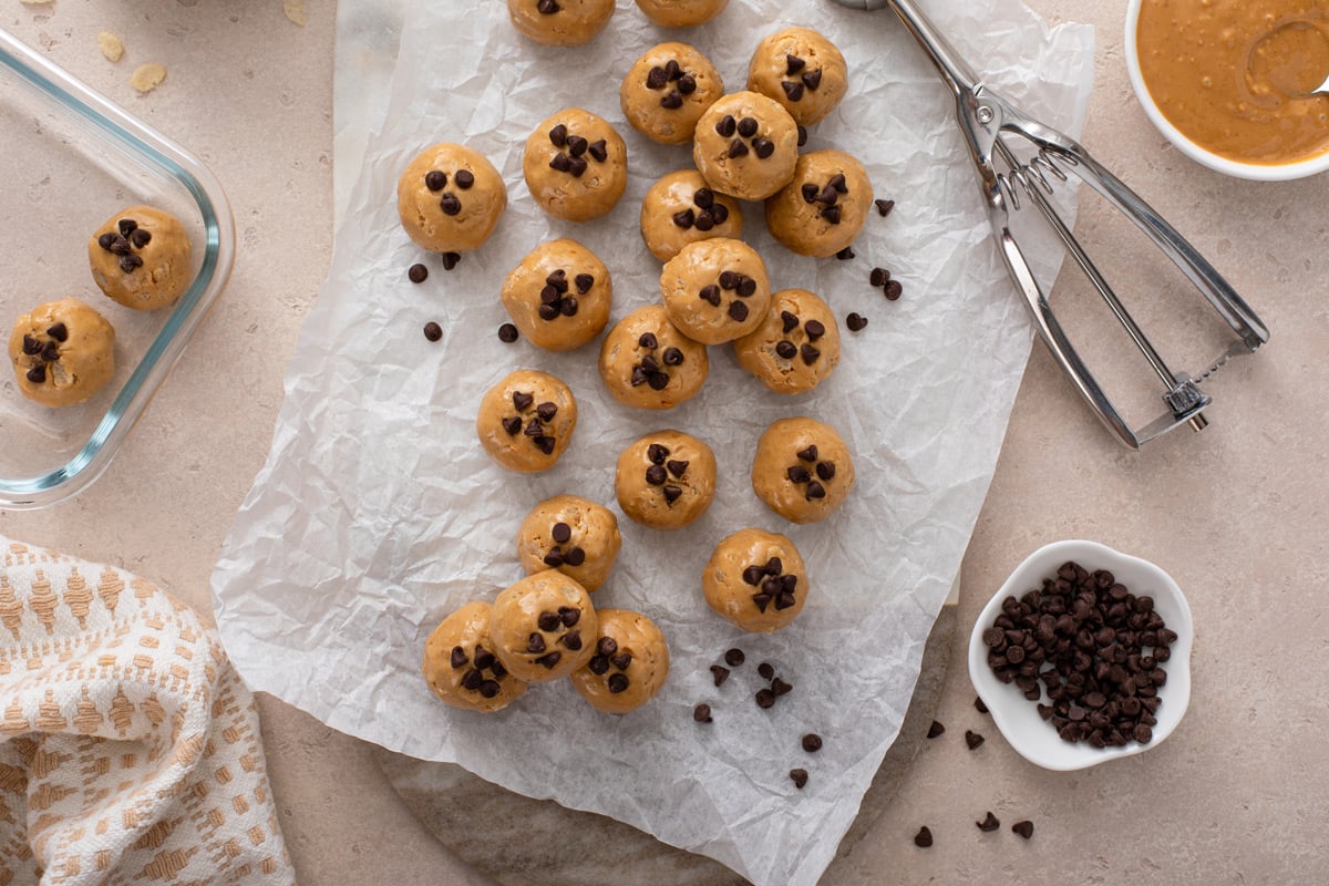 Peanut butter protein balls topped with mini chocolate chips and arranged on a piece of parchment paper.