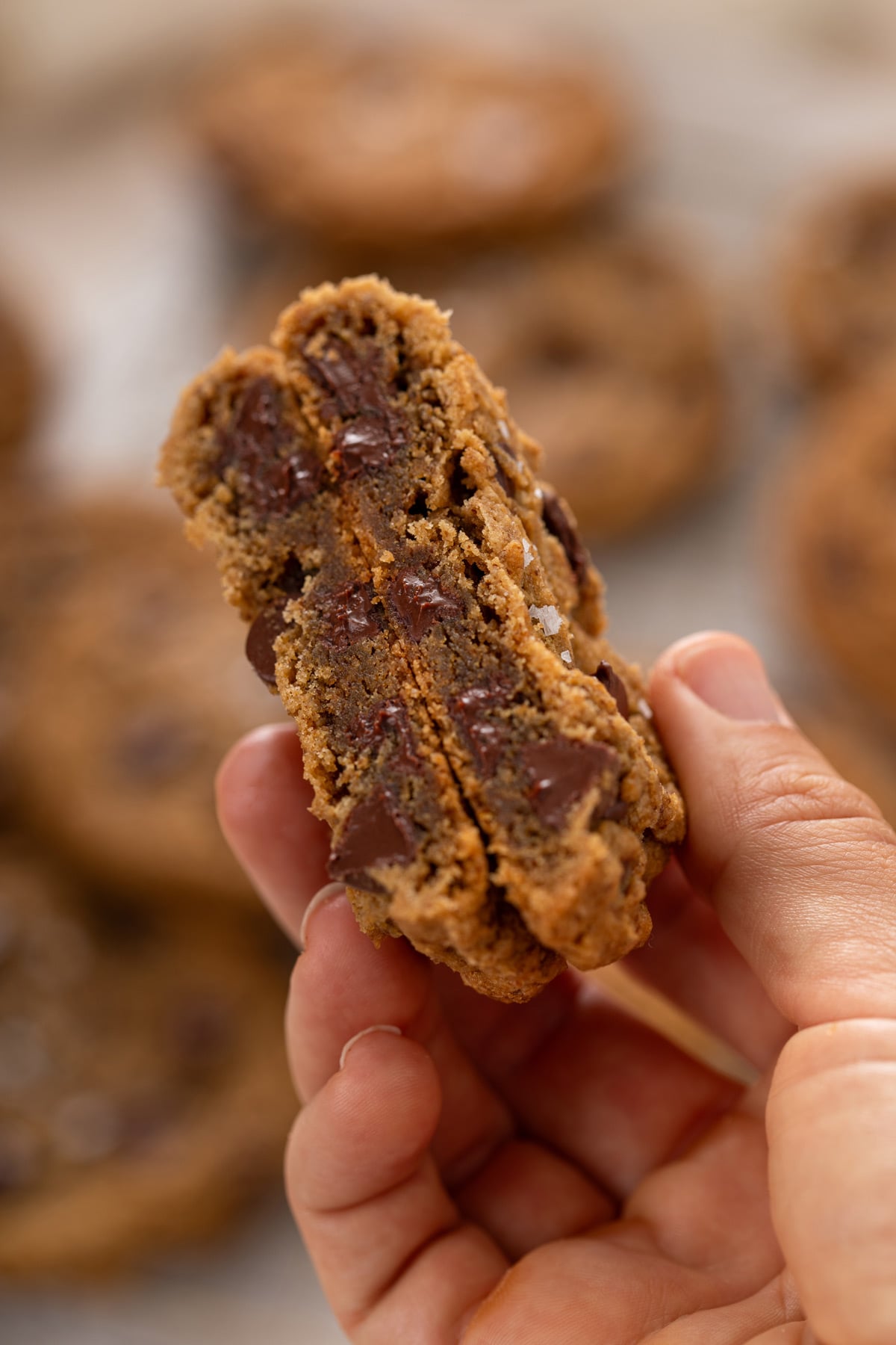 Hand holding up a halved espresso chocolate chip cookie to show the chewy interior.