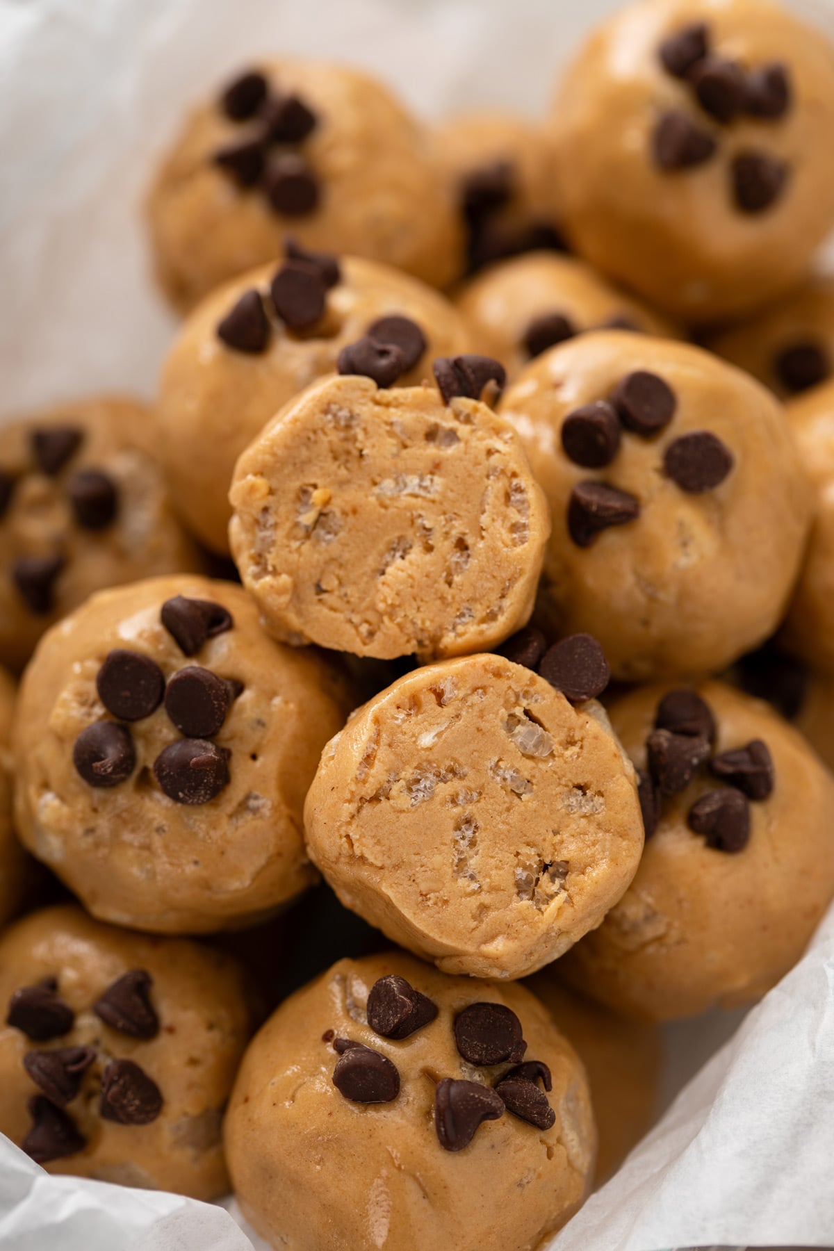 Halved peanut butter protein ball set on top of a pile of the bites.