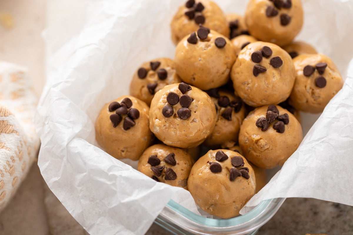Peanut butter protein balls arranged in a parchment-lined glass container.
