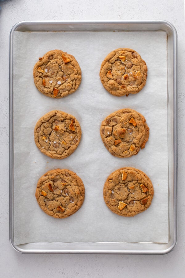 6 freshly baked caramel apple cookies on a parchment lined baking sheet.