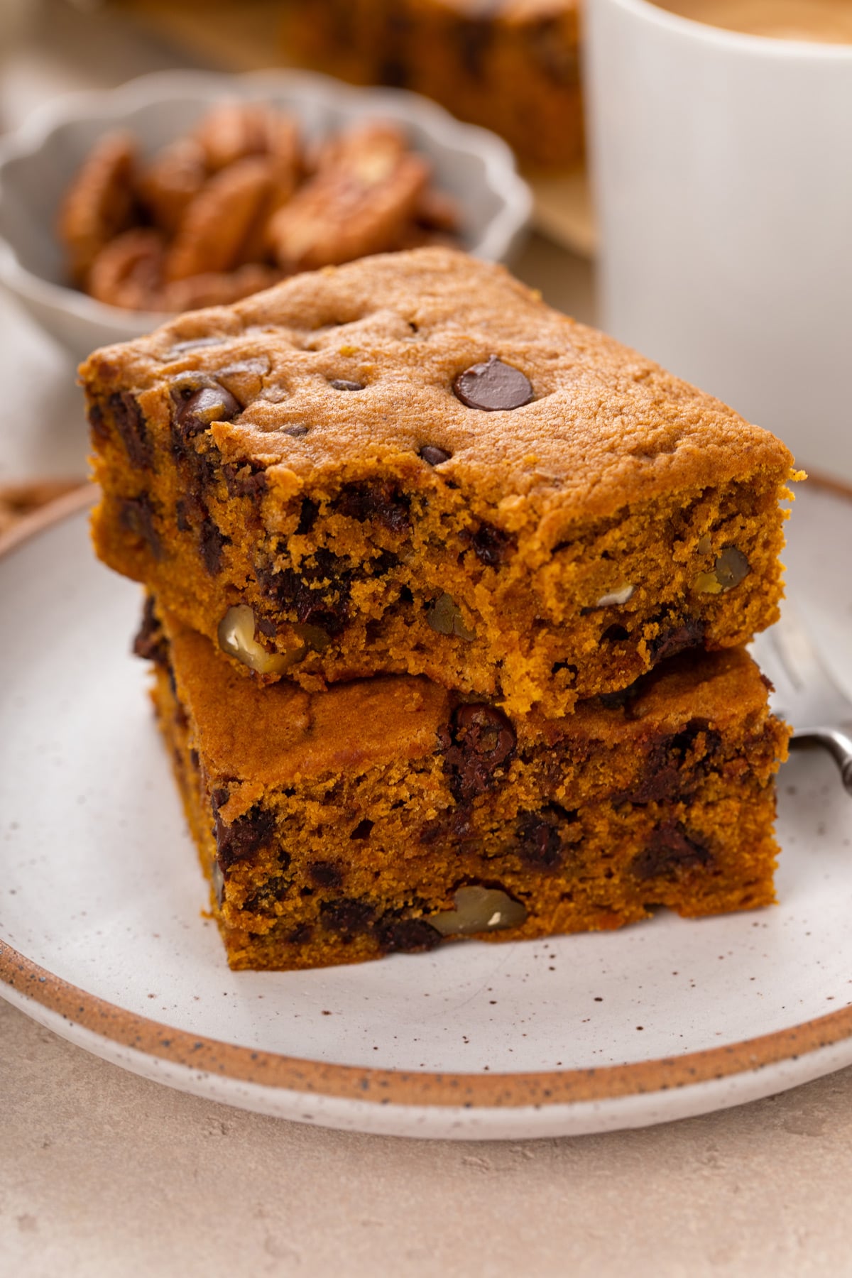 Two slices of stacked pumpkin snack cake on a plate with a bite taken from the corner of the top piece.