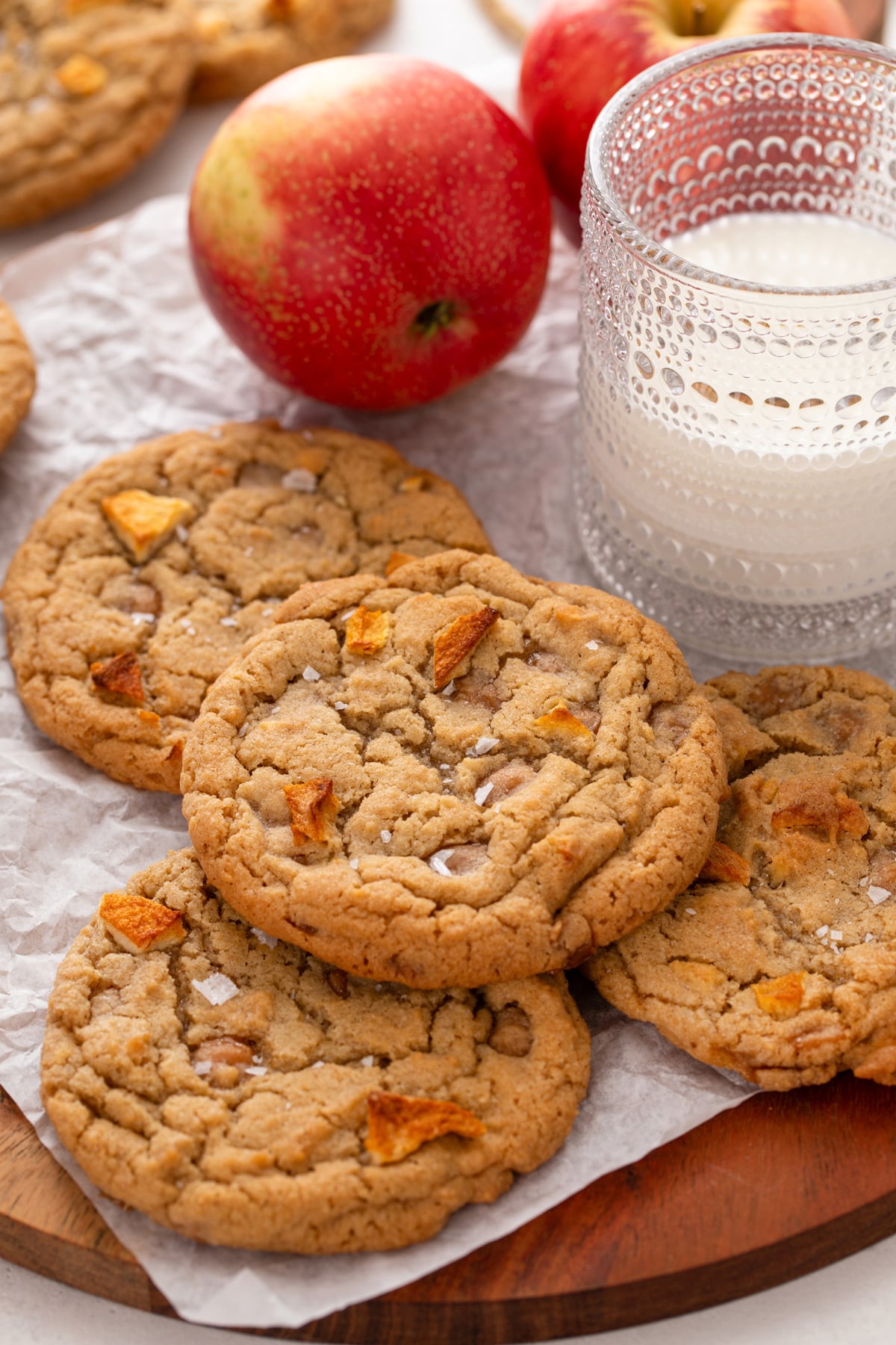 Several caramel apple cookies arranged next to a glass of milk.
