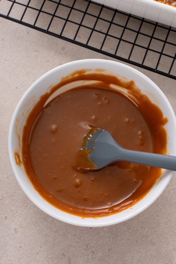 Melted caramel bits in a bowl to drizzle over caramel apple dump cake.