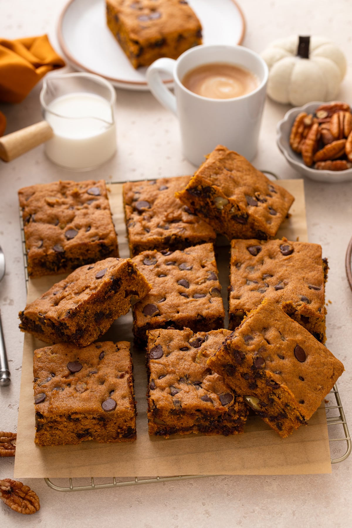 9 slices of pumpkin chocolate chip snack cake arranged on a piece of parchment paper over a wire rack.