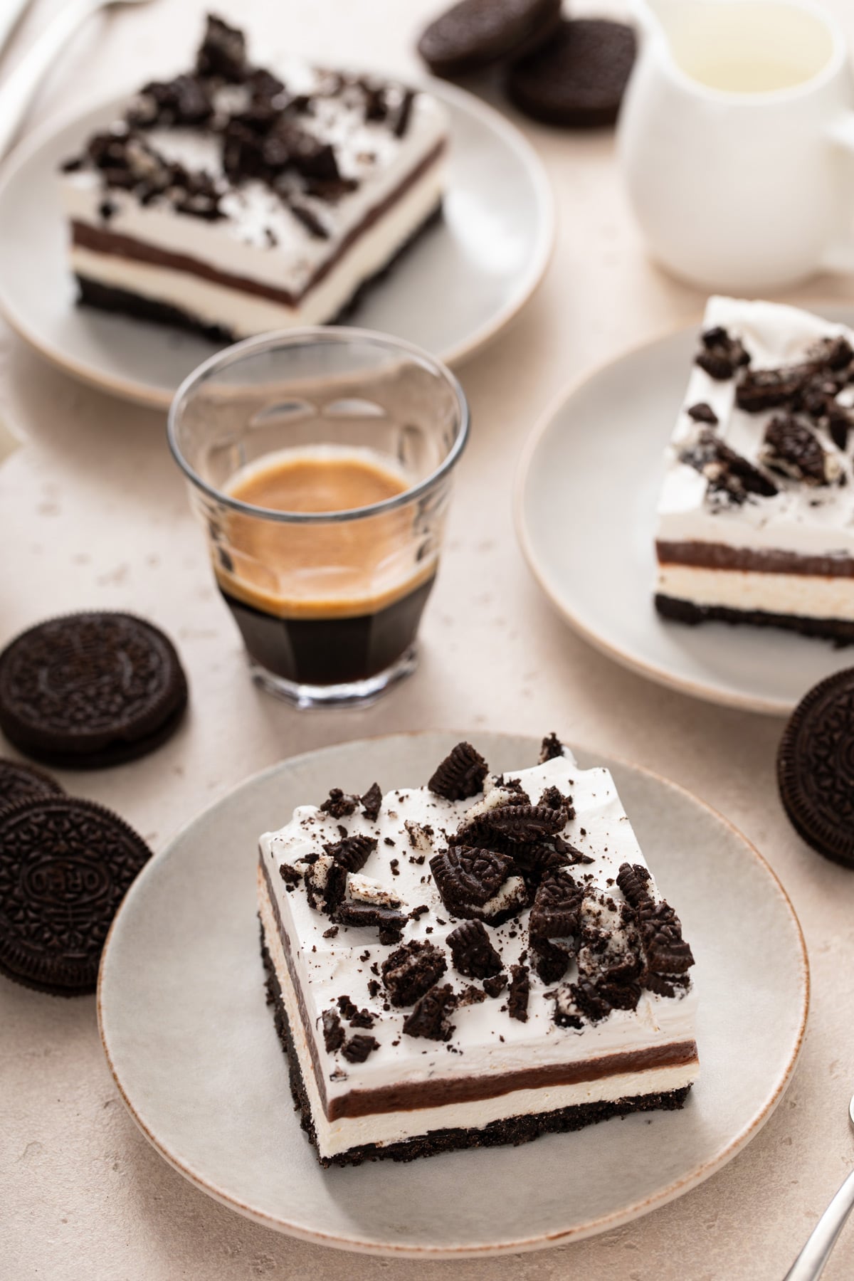 Three white plates on a countertop, each holding a slice of layered chocolate pudding dessert.
