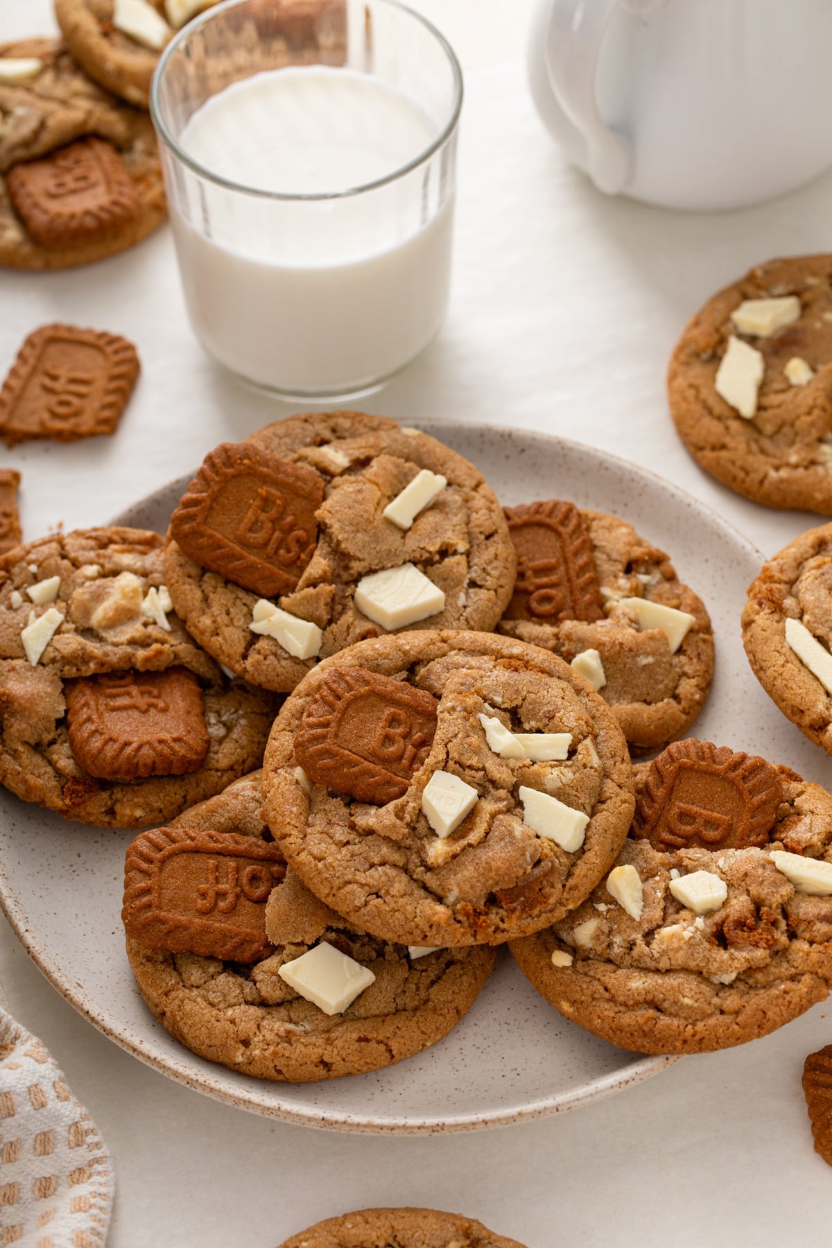 Plate filled with cookie butter cookies with a glass of milk in the background.