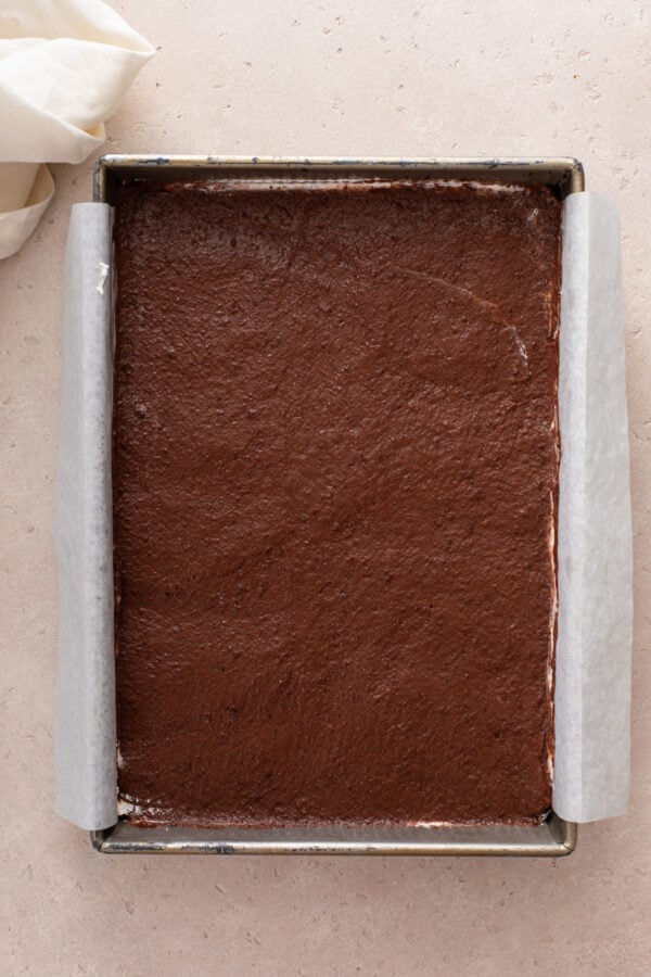 Chocolate pudding spread in an layer in a parchment-lined baking pan.