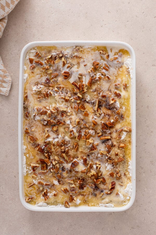 Melted butter drizzled on top of unbaked caramel apple dump cake, ready to go in the oven.