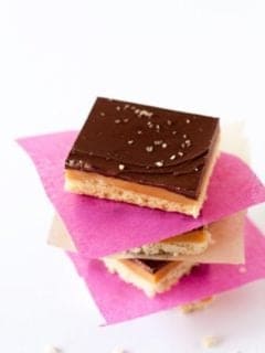 Three pieces of Caramel shortbread stacked with pink and white paper in between