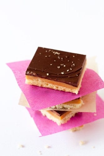 Three pieces of Caramel shortbread stacked with pink and white paper in between