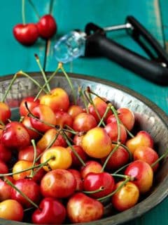 Bowl of fresh cherries in front of a cherry pitter