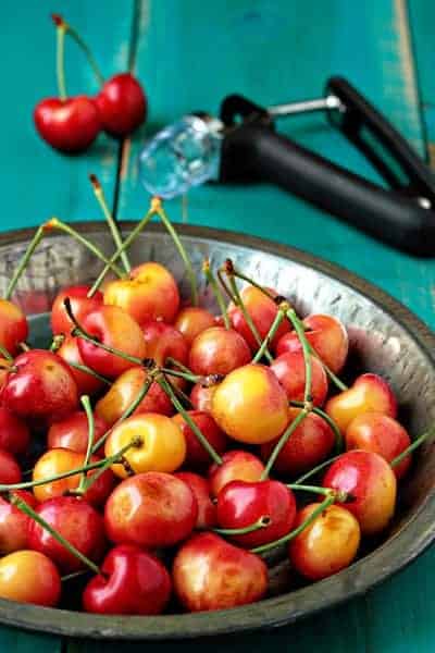 Bowl of fresh cherries in front of a cherry pitter