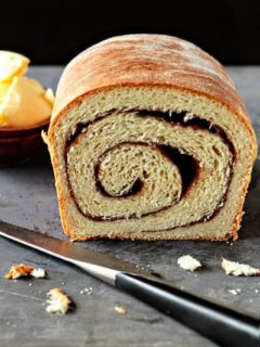 Cut loaf of cinnamon bread on a stone surface with a knife
