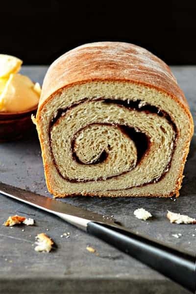 Cut loaf of cinnamon bread on a stone surface with a knife