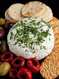 Feta cheese ball next to crackers and olives