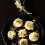 Stuffed mushrooms in a cast iron skillet with a black background