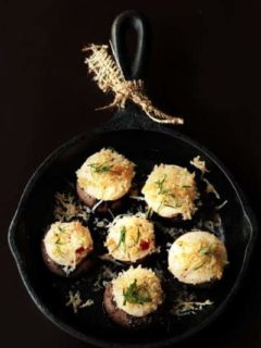 Stuffed mushrooms in a cast iron skillet with a black background