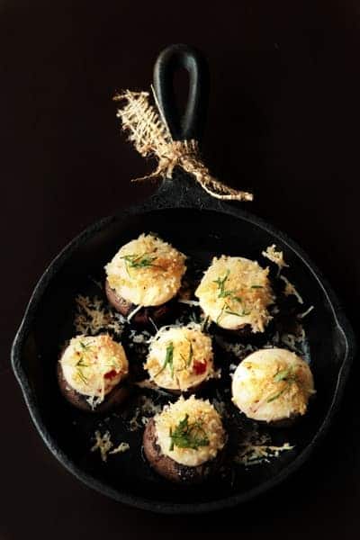 Stuffed mushrooms in a cast iron skillet with a black background