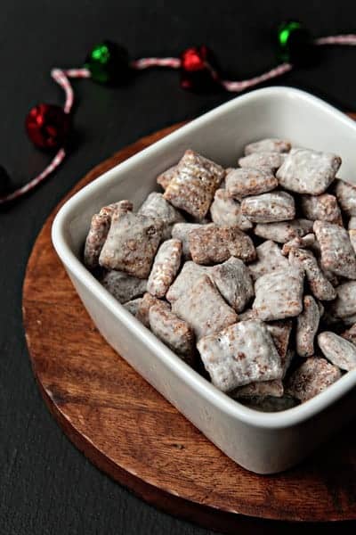 Square bowl full of reindeer chow on a round wood surface