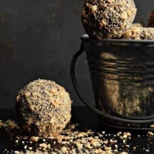 Small metal bucket filled with s'mores truffles with a truffle next to it on a black surface