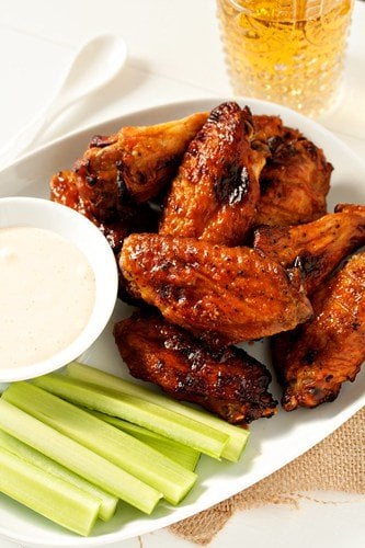 Sweet and spicy baked chicken wings on a plate with celery and a dipping sauce